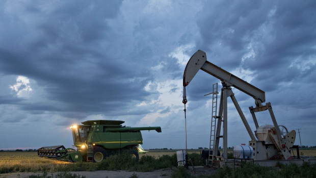A Deere & Co. John Deere combine harvester drives past a pumpjack in the Bemis-Shutts oil field during the harvest of hard red winter wheat in Plainville, Kansas, U.S., on Wednesday, June 28, 2017. Spring wheat prices posted wide swings after reaching a four-year high as traders weighed prospects for an intensifying drought in the High Plains against signs that U.S. supplies aren't competitive in export markets. Photographer: Daniel Acker/Bloomberg