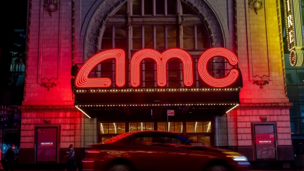 A vehicle passes in front of an AMC movie theater at night in the Times Square neighborhood of New York, U.S., on Tuesday, Oct. 15, 2020. AMC Entertainment Holdings Inc. is considering a range of options that include a potential bankruptcy to ease its debt load as the pandemic keeps moviegoers from attending and studios from supplying films.
