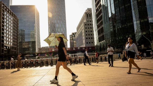 A pedestrian uses a umbrella to protect herself from the sun, at Canary Wharf, during a heatwave in London, UK, on Monday, July 18, 2022. Extreme heat could lead to power outages, canceled flights and may be a danger to life while the so-called Red Extreme warning is in place across parts of southern England on Monday and Tuesday. Photographer: Jose Sarmento Matos/Bloomberg