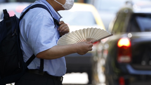A pedestrian holding a folding fan in the Marunouchi district of Tokyo, Japan, on Friday, July 1, 2022. The government issued a heat stroke alert for several regions in the country including the nation’s capital, urging people to take health precautions amid scorching temperatures.