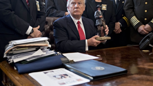 U.S. President Donald Trump holds up a statue he received as a gift while meeting with county sheriffs in the Oval Office of the White House in Washington, D.C., U.S., on Tuesday, Feb. 7, 2017. The Trump administration will return to court Tuesday to argue it has broad authority over national security and to demand reinstatement of a travel ban on seven Muslim-majority countries that stranded refugees, triggered protests and handed the young government its first crucial test.