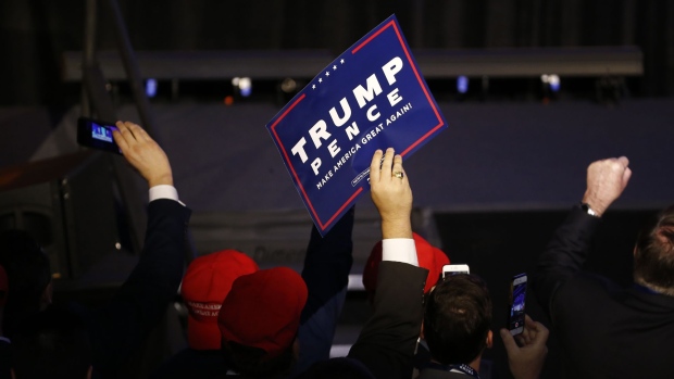 An attendee holds a campaign sign during an election night party for 2016 Republican Presidential Nominee Donald Trump at the Hilton Midtown hotel in New York, U.S., on Tuesday, Nov. 8, 2016. Fifty-one percent of voters nationally were bothered a lot by Trump's treatment of women, while Democrat Hillary Clinton's use of private e-mail while secretary of state was troubling to 44 percent, according to preliminary exit polling as voting neared a close in some states. Photographer: Andrew Harrer/Bloomberg