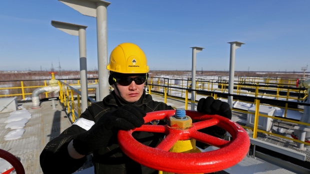 A worker turns a flow valve near oil storage tanks at a pumping station, operated by Rosneft PJSC, in the Samotlor oilfield near Nizhnevartovsk, Russia, on Monday, March 20, 2017. Russia's largest oil field, so far past its prime that it now pumps almost 20 times more water than crude, could be on the verge of gushing profits again for Rosneft PJSC.