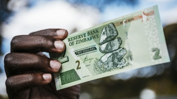 A man holds a Zimbabwean two dollar bond banknote for an arranged photograph in Harare, Zimbabwe, on Tuesday, July 31, 2018. Zimbabwe's main opposition party said it was well ahead in the first election of the post-Robert Mugabe era and it's ready to form the next government, as unofficial results began streaming in. Photographer: Waldo Swiegers/Bloomberg