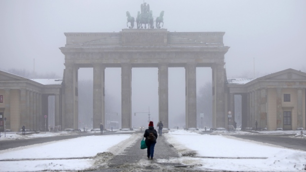 A pedestrian walks through snow near the Brandenburg Gate in central Berlin, Germany, on Tuesday, Feb. 16. 2021. Representatives of German industry protested in central Berlin on the day, when the country’s top business lobbies hold talks with Economy Minister Peter Altmaier.