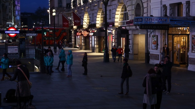 Pedestrians walk through Piccadilly Circus in the West End district in London, U.K., on Friday, March 20, 2020. A shutdown of the U.K. capital would hit the night-time economy hard -- one in three employees in London works between 6 p.m. and 6 a.m., many in the pubs, restaurants and clubs most at risk of survival because of the pandemic. Photographer: Simon Dawson/Bloomberg