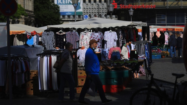 Shoppers pass a clothes market stall near a Stadtsparkasse bank branch in Magdeburg, Germany, on Thursday, May 28, 2020. German Chancellor Angela Merkel’s government is preparing a bundle of measures to put Europe’s largest economy back on track after a nosedive triggered by the coronavirus pandemic. Photographer: Krisztian Bocsi/Bloomberg