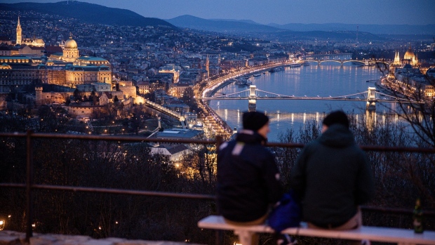 Visitors look out over the city skyline and the Chain Bridge at night in Budapest, Hungary, on Tuesday, March 9, 2021. Prime Minister Viktor Orban severely tightened curbs, closing schools and nearly all retail outlets from Monday. Photographer: Akos Stiller/Bloomberg