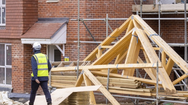 A builder passes roof trusses stored on a residential property construction site in Surrey, U.K. on Tuesday, Feb. 8, 2022. The housing market has defied the plight of the wider economy since the pandemic began, boosted by temporary tax incentives, a shortage of stock and demand for properties outside urban areas with room to work from home. Photographer: Jason Alden/Bloomberg