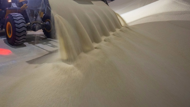 A worker operates a front end loader to move granules of phosphate fertilizer in a storage warehouse at a fertilizer plant, in Cherepovets, Russia.