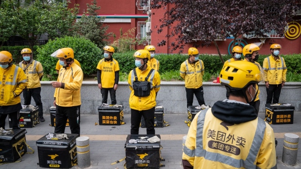 Food delivery couriers for Meituan stand with insulated bags during a morning briefing in Beijing, China, on Wednesday, April 21, 2021. Chinese delivery giant Meituan has raised $9.98 billion from a record top-up placement and a convertible bonds sale as it doubles down on efforts to fight the likes of Alibaba Group Holding Ltd. in newer areas such as online groceries.