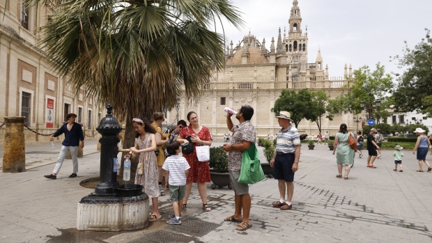 Visitors to Seville fill their water bottles from a public fountain during a heat wave in June. Photographer: Marcelo del Pozo/Bloomberg