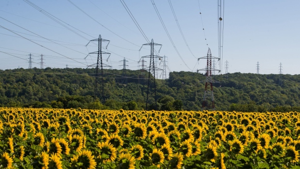 Electricity power lines above a field of sunflowers near the decomissioned Porcheville fuel power plant, operated by Electricite de France SA (EDF), in Porcheville, France, on Friday, July 8, 2022. The French government will nationalize its financially struggling nuclear giant Electricite de France SA to help it ride out Europe’s worst energy crisis in a generation and invest in new atomic plants. Photographer: Nathan Laine/Bloomberg