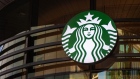 A logo hangs above the entrance to a Starbucks Corp. cafe in the Sandton area of Johannesburg, South Africa, on Monday, Jan. 14, 2019. While South Africa's economy emerged from a recession in the third quarter, growth remains sluggish, hampered by subdued business confidence, higher taxes imposed by the government in February and a tight monetary-policy stance. Photographer: Waldo Swiegers/Bloomberg