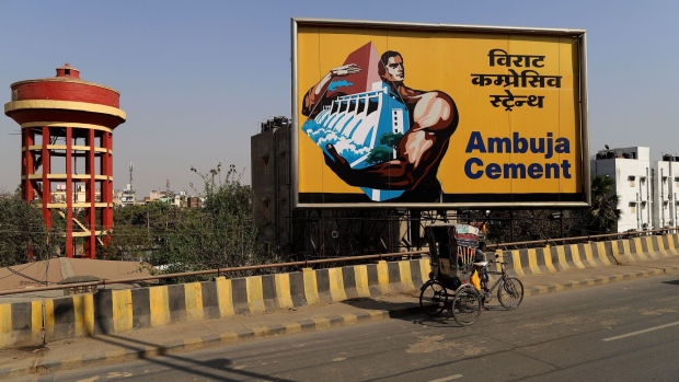 A rickshaw-puller travels past an Abuja Cements Ltd. billboard on a highway in Patna, Bihar, India, on Thursday, Feb. 25, 2021. After falling into a coronavirus-fueled recession in the third quarter, India's economy has likely returned to expansion in the three months ended December, according to the median estimate in a Bloomberg survey of economists.