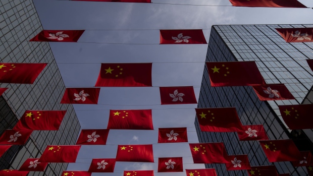 The flags of China and the Hong Kong Special Administrative Region (HKSAR) displayed in Tsim Sha Tsui district to mark National Day in Hong Kong, China, on Friday, Oct. 1, 2021. Hong Kong is putting more police on its streets during this year’s National Day celebrations than it did for the same holiday during historic unrest two years ago, evidence of the laser focus authorities are placing on eliminating any sign of dissent in the financial hub. Photographer: Paul Yeung/Bloomberg