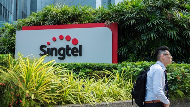 A man walks past signage for Singapore Telecommunications Ltd. (Singtel) in Singapore, on Friday, July 6, 2018. Singtel, Southeast Asia’s largest telecom services provider, will start a regional competitive gaming league as part of its diversification into e-sports and digital content. Photographer: Nicky Loh/Bloomberg