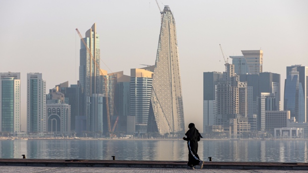 A resident jogs along the corniche backdropped by commercial and residential skyscrapers in Doha, Qatar, on Thursday, June 23, 2022. About 1.5 million fans, a little more than half the population of Qatar, are expected to descend upon the tiny Gulf state for this year's FIFA World Cup football tournament. Photographer: Christopher Pike/Bloomberg