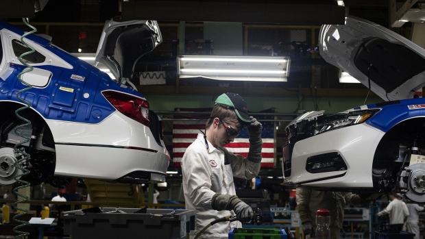 A production associate adjusts his hat while working between 2018 Honda Accord vehicles during production at the Honda of America Manufacturing Inc. Marysville Auto Plant in Marysville, Ohio, U.S., on Thursday, Dec. 21, 2017. More than three decades after Honda Motor Co. first built an Accord sedan at its Marysville factory in 1982, humans are still an integral part of the assembly process -- and that's unlikely to change anytime soon. Photographer: Ty Wright/Bloomberg