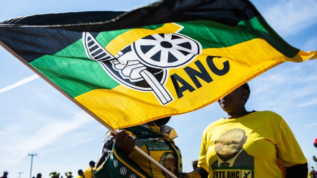 A pedestrian carries an ANC flag during the 54th national conference of the African National Congress party in Johannesburg, South Africa, on Sunday, Dec. 17, 2017. The leadership conference of South Africa’s ruling African National Congress party has accepted the credentials of the delegates, opening the way for the start of voting to choose the party’s top officials, according to five people familiar with the deliberations. Photographer: Waldo Swiegers/Bloomberg