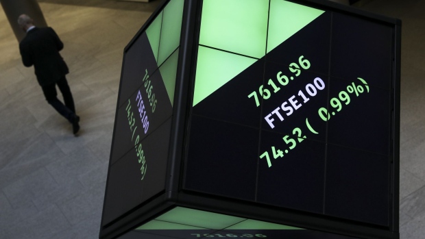 An employee walks past FTSE100 share price information displayed on an illuminated rotating cube in the atrium of the London Stock Exchange Group Plc's offices in London, U.K., on Thursday, Jan. 2, 2020. Stocks started the year on the front foot, building on strong gains for many asset classes in 2019 as investors cheered the latest policy move by China’s central bank to support its economy. Photographer: Simon Dawson/Bloomberg