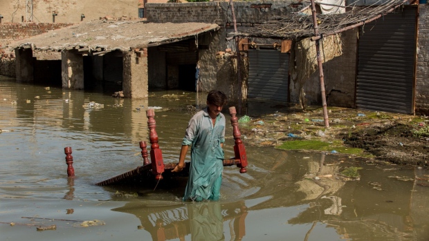 A man carries furniture through flood water at Goth Muhammad Yusuf Naich in Dadu district, Sindh province, Pakistan, on Thursday, Sept. 1, 2022. Pakistan is facing a humanitarian crisis after unprecedented rainfall led to ongoing flooding that has inundated about a third of the country and left more than 1,100 people dead since June.