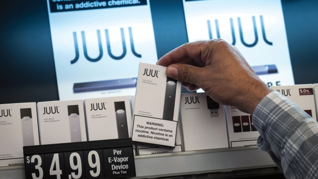 An employee picks up a Juul Labs Inc. device kit for a customer at a store in San Francisco, California, U.S., on Wednesday, June 26, 2019. The city voted Tuesday to ban sales of e-cigarettes, making it illegal to sell nicotine vaporizer products in stores or for online retailers to ship the goods to San Francisco addresses.