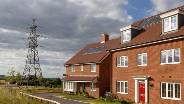 An electricity transmission tower near new residential homes with solar panels installed in Rayleigh, UK, on Monday, July 4, 2022. The UK is set to water down one of its key climate change policies as it battles soaring energy prices that have contributed to a cost-of-living crisis for millions of consumers.