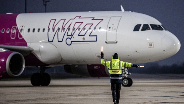 A member of ground crew directs a Wizz Air Holdings Plc passenger aircraft to the gate at Debrecen International Airport in Debrecen, Hungary, on Thursday, Dec. 17, 2020. Hungarians may take part in the clinical trial of Russia’s Sputnik V coronavirus vaccine, according to the top health official of the eastern European Union member state.