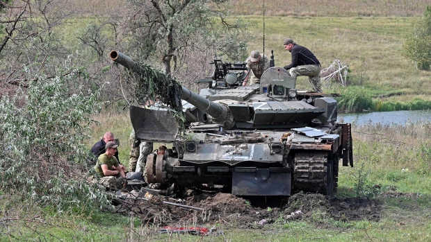 Ukrainian servicemen work on a tank abandoned by Russian troops during their retreat in the north of the Kharkiv region, on Sept. 20. Photographer: Sergey Bobok/AFP/Getty Images