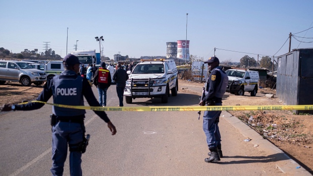 South African Police Service (SAPS) officers enforce a perimeter around a crime scene as pathalogical investigators inspect the crime scene where 14 people where shot dead in a tavern as a forensic team investigates in Soweto on July 10, 2022. Photographer: Emmanuel Croset/AFP/Getty Images