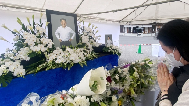 A mourner pays tribute to late former Prime Minister Shinzo Abe at a makeshift memorial at the Zojoji temple in Tokyo, Japan, on Tuesday, July 12, 2022. The funeral will be for the family and close associates of Abe, who was fatally shot at close range last Friday as he was making an election campaign speech outside a train station in the western city of Nara. Larger-scale memorial services are to be held at a later date.