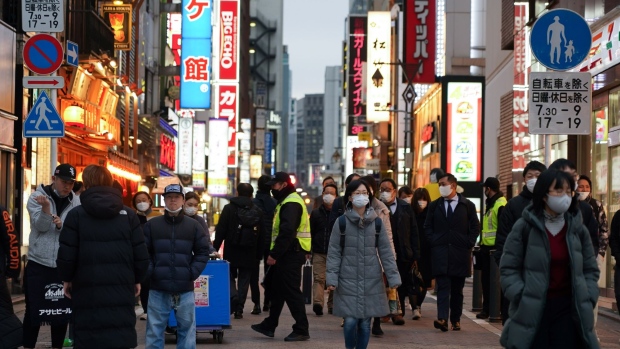 Pedestrians wearing protective face masks pass bars and restaurants in the Shimbashi District of Tokyo, Japan, on Wednesday, March 23, 2022. Japan’s government on Tuesday lifted quasi-state of emergency measures in Tokyo and other regions across the country, bringing to an end steps introduced in early January as cases continue to tumble.