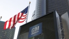 An American flag flies near General Motors Co. signage outside the company's Renaissance Center world headquarters complex in Detroit, Michigan, U.S., on Tuesday, June 12, 2018. The automaker still has a financial investment in Lyft Inc. but has no active projects underway with the ride-hailing platform, said GM chairman and chief executive Mary Barra before the company's annual shareholders meeting. Photographer: Jeff Kowalsky/Bloomberg