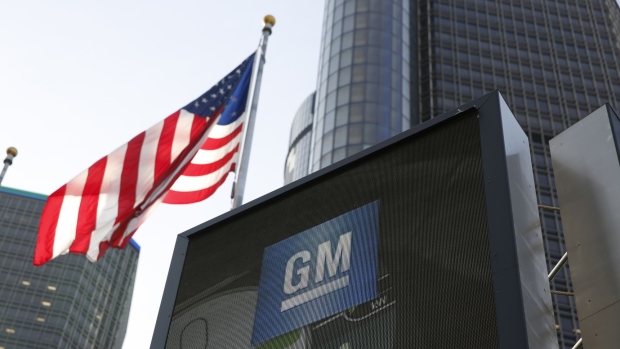 An American flag flies near General Motors Co. signage outside the company's Renaissance Center world headquarters complex in Detroit, Michigan, U.S., on Tuesday, June 12, 2018. The automaker still has a financial investment in Lyft Inc. but has no active projects underway with the ride-hailing platform, said GM chairman and chief executive Mary Barra before the company's annual shareholders meeting. Photographer: Jeff Kowalsky/Bloomberg
