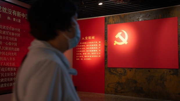 A visitor walks past a Chinese Communist Party flag at an exhibition celebrating the Party's centenary at The China Millennium Monument in Beijing, China, on Friday, June 25, 2021. The Communist Party will celebrate 100 years since its founding on July 1, an occasion which President Xi Jinping is also using to showcase his own grip over the ruling party. Photographer: Yan Cong/Bloomberg