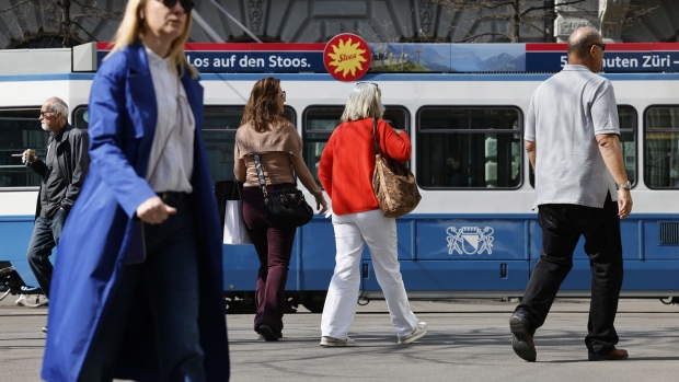 A tram passes morning commuters and shoppers in Zurich, Switzerland, on Monday, March 28, 2022. Switzerland trimmed its growth outlook for 2022, citing the economic fallout of Russia’s invasion of Ukraine and faster inflation.
