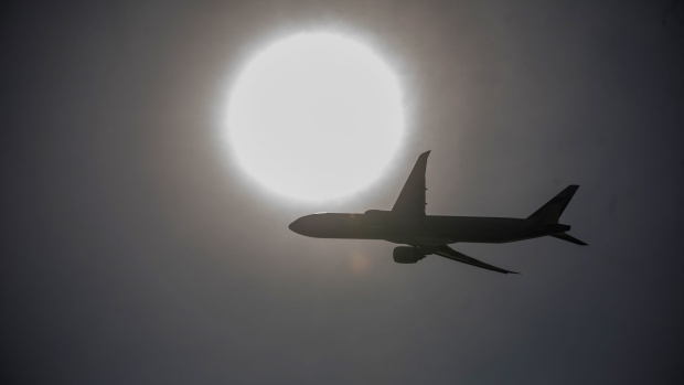 An aircraft is silhouetted as it flies over the Hong Kong International Airport in Hong Kong, China, on Tuesday, Dec. 3, 2019. Hong Kong is likely to hold on to its status as the world's most popular city with international visitors in 2019, despite months of political unrest that led to a sharp drop in tourist numbers. Photographer: Paul Yeung/Bloomberg