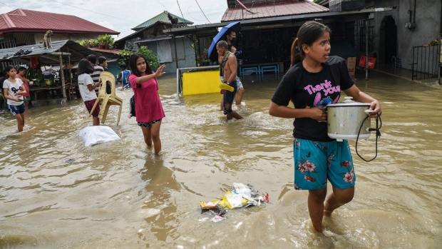 Residents carry their belongings while evacuating from their submerged homes in the aftermath of Super Typhoon Noru in San Ildefonso, Bulacan province on September 26, 2022. Photographer: Ted Aljibe/AFP/Getty Images