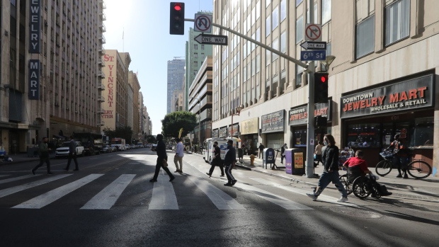 Pedestrians cross a street in downtown Los Angeles, California, U.S., on Thursday, Dec. 3, 2020. Los Angeles Mayor Eric Garcetti issued an order for residents to stay at home, warning that the city is approaching a “devastating tipping point” in its fight against Covid-19 that would overwhelm the hospital system.