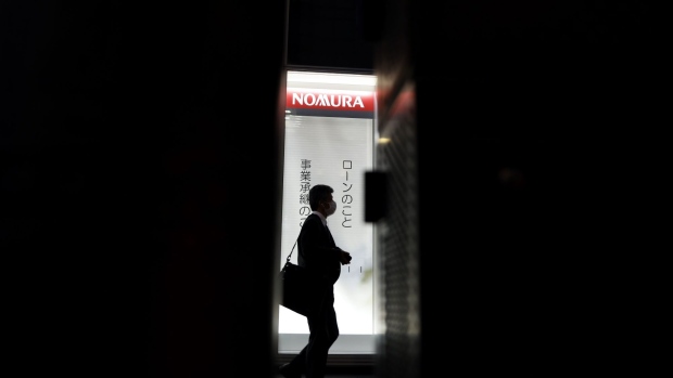 A pedestrian in front of a branch of Nomura Securities Co., a unit of Nomura Holdings Inc., at dusk in Tokyo, Japan, on Monday, April 25, 2022. Nomura Holdings is scheduled to release earnings figures on April 25. Photographer: Kiyoshi Ota/Bloomberg