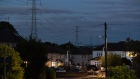 Electricity transmission towers near residential houses with lights on in Upminster, UK, on Monday, July 4, 2022. The UK is set to water down one of its key climate change policies as it battles soaring energy prices that have contributed to a cost-of-living crisis for millions of consumers.