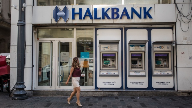A pedestrian walks past automated teller machines (ATM) outside a branch of the Turkiye Halk Bankasi AS, also known as Halkbank, in Istanbul, Turkey, on Monday, Aug. 13, 2018. President Recep Tayyip Erdogan vowed to boycott iPhones in a demonstration of defiance as the U.S. held firm to its demand that Turkey release an evangelical pastor and Turkish executives called for action to bolster the lira.