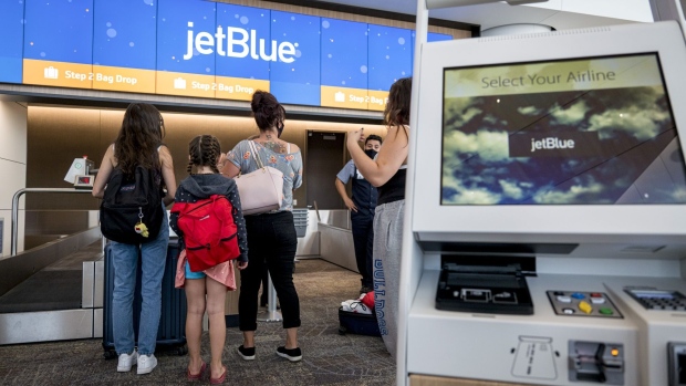 Travelers wearing protective masks stand at a JetBlue Airways Corp. check-in counter at San Francisco International Airport (SFO) in San Francisco, California, U.S., on Friday, July 17, 2020. Jet Blue Airways Corp. is scheduled to release earnings figures on July 28. Photographer: David Paul Morris/Bloomberg