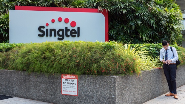 A man stands next to signage for Singapore Telecommunications Ltd. (Singtel) in Singapore, on Friday, July 6, 2018. Singtel, Southeast Asia’s largest telecom services provider, will start a regional competitive gaming league as part of its diversification into e-sports and digital content. Photographer: Nicky Loh/Bloomberg