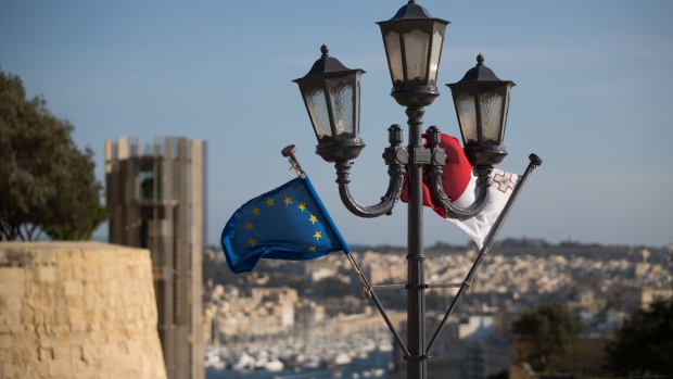 The European Union (EU) flag, left, and the national flag of Malta fly as luxury vessels sit moored beyond at Vittoriosa Yacht Marina beyond, in Valletta, Malta, on Thursday, Feb. 2, 2017. It may be smaller than the smallest English county, but Malta provides an insight into the European allegiances that Britain will hit head on after firing the starting gun on Brexit negotiations in coming weeks. Photographer: Jasper Juinen/Bloomberg