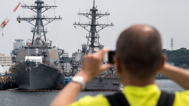 YOKOSUKA, JAPAN - JUNE 01: A man takes a photograph of naval ships including the USS John S. McCain (DDG 56) destroyer (L) moored at the Yokosuka Naval Base on June 01, 2019 in Yokosuka, Japan. On Thursday, U.S. President Donald Trump has denied any involvement the move to hide the Navy Ship USS John S. McCain during his recent visit to its home port in Yokosuka, after reports emerged of emails being exchanged about keeping the ship out of view. Nicknamed “Big Bad John,” the McCain is a 505 feet long destroyer that honors late U.S. Senator John McCain and has a crew of 338 people. The ship was reportedly part of the U.S.’s invasion of Iraq in 2003 and participated in relief efforts after an earthquake struck Japan in 2011. (Photo by Tomohiro Ohsumi/Getty Images)