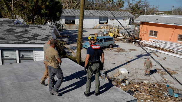 First responders walk on the debris of a house at the marina at San Carlos Maritime Park following Hurricane Ian in Fort Myers, Florida, US, on Friday, Sept. 30, 2022. Two million electricity customers in Florida remained without power Friday morning, according to the tracking site poweroutage.us.