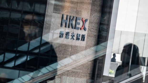 People wearing protective masks walk past signage for Hong Kong Exchanges & Clearing Ltd. (HKEX) displayed at the Exchange Square complex in Hong Kong, China, on Wednesday, Aug. 19, 2020. HKEX posted a 1% gain in profit, benefiting from a spate of high-profile Chinese stock listings and a pick up in trading as the pandemic and political tensions stoked volatility. Photographer: Roy Liu/Bloomberg