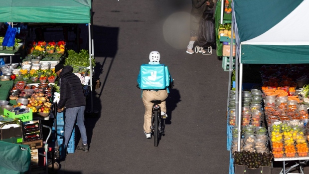 A food delivery courier for Deliveroo Plc cycles past market stalls selling fresh fruit and vegetables in Croydon, Greater London, U.K., on Monday, Jan. 17, 2022. Inflation figures for the U.K., due on Wednesday, are likely to hold steady in December, before peaking in April at around 6.5%.
